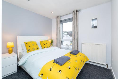 a bedroom with a bed with yellow pillows and a window at Lovely 3-bedroom flat with free parking in Bridge of Allan