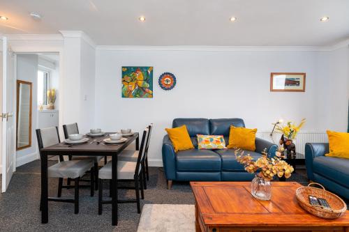 a living room with a blue couch and a table at Lovely 3-bedroom flat with free parking in Bridge of Allan