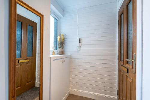um corredor com paredes brancas e uma porta de madeira em Lovely 3-bedroom flat with free parking em Bridge of Allan