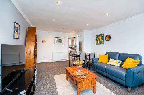 a living room with a blue couch and a table at Lovely 3-bedroom flat with free parking in Bridge of Allan