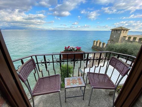 a balcony with chairs and a table and the ocean at Hotel Grifone in Sirmione