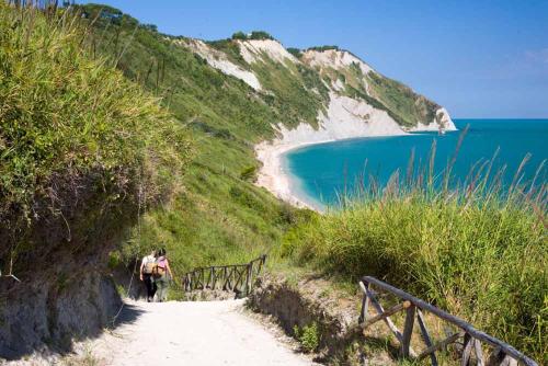 a couple of people walking down a dirt path next to a beach at LoLè Apartment - Ancona in Ancona