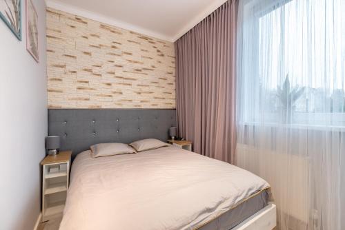 Habitación pequeña con cama y ventana en Victus Apartamenty, Apartament Playa De Sopot, en Sopot