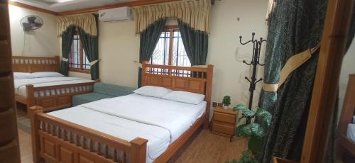a small bedroom with two beds and a couch at Eagle Nest Cottage Muzaffarabad by LMC in Muzaffarabad
