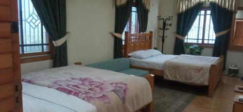 a bedroom with two beds and a chair and windows at Families Only! Eagle Nest Cottage Muzaffarabad by LMC in Muzaffarabad