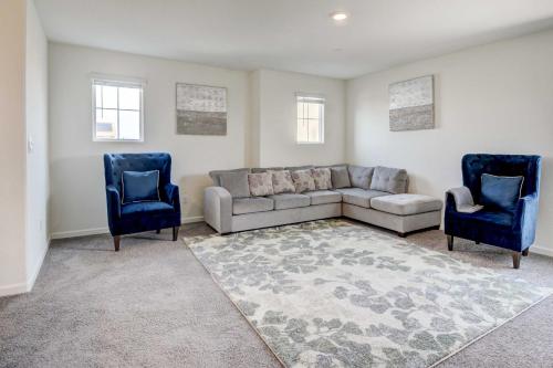 a living room with a couch and two blue chairs at Spacious Merced Vacation Rental! in Merced