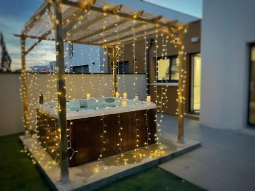 um deque com uma banheira de hidromassagem com luzes em Le GREEN'SPA - DIJON - SPA-jardin-parking privé em Longvic