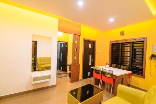 a living room with yellow walls and a kitchen with a table at Rinad Castle Vythiri By Hamra Retreat in Vythiri