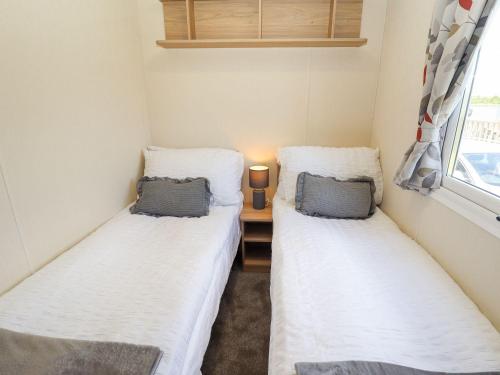 two twin beds in a small room with a window at 3 Bed New Lodge - 7 Lakes Country Park DN17 in Scunthorpe