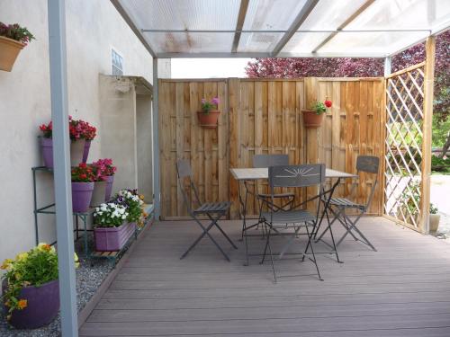 een patio met een tafel en stoelen en potplanten bij Le Tamaris in Die