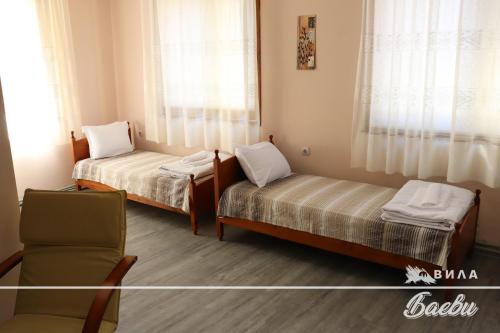 ヴェリングラードにあるВИЛА БАЕВИのベッド2台と椅子が備わる小さな客室です。