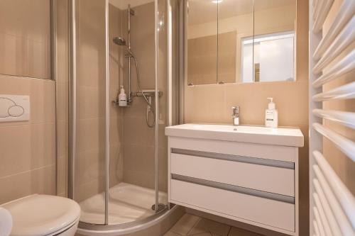 een badkamer met een douche, een wastafel en een toilet bij Haus Dünenrand, App 2 in Wenningstedt