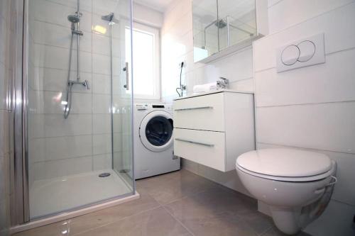 a bathroom with a toilet and a shower and a washing machine at Apartments Ane 1 Tisno in Tisno