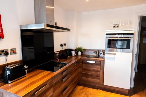 La cuisine est équipée de comptoirs en bois et d'un four avec plaques de cuisson. dans l'établissement Apartment @ I Quarter, à Sheffield
