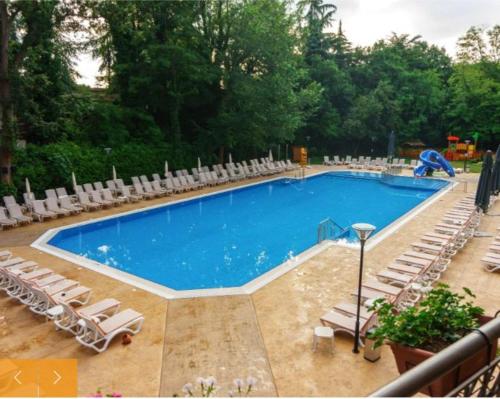 uma grande piscina com cadeiras e um monte de móveis em Private Apartment in Golden Sands - Aquamarine Odessos em Golden Sands