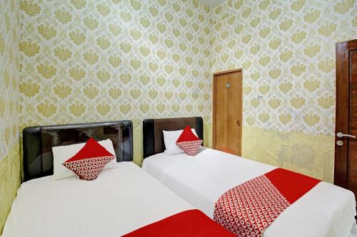 2 camas con almohadas rojas y blancas en una habitación en OYO Life 92312 A+ Cozy Rooms Syariah, en Kediri