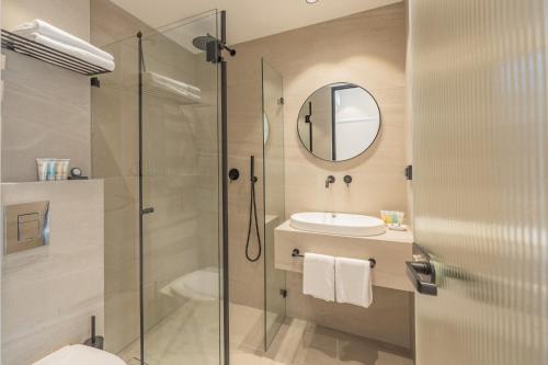 a bathroom with a shower and a sink and a mirror at The Arbel Tel Aviv in Tel Aviv