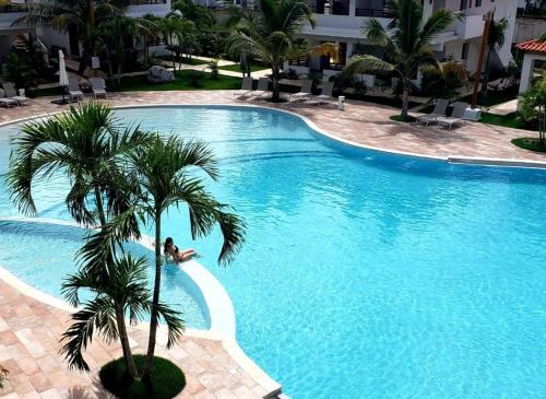 Una gran piscina con una palmera al lado de un edificio. en Paraiso Bayahibe by Mireya, en Bayahibe