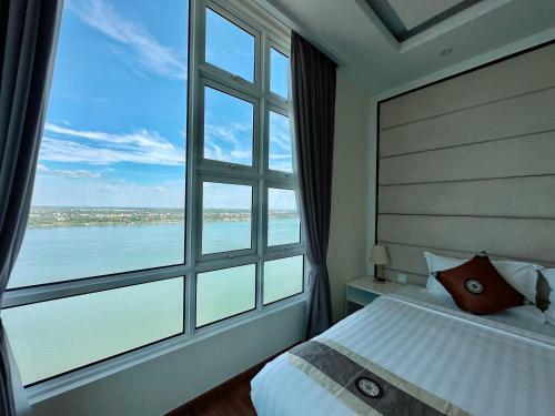 a bedroom with a large window overlooking the water at Infinity 28 Hotel and Residence in Phnom Penh