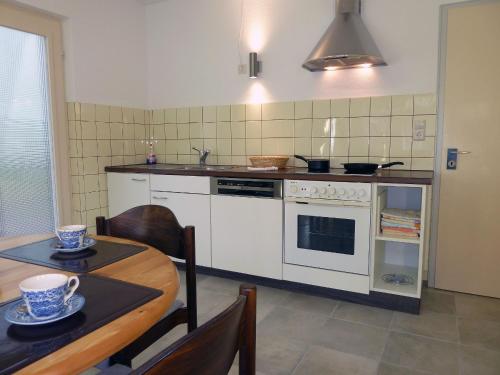 a kitchen with a white stove and a table with a dining room at Ferienwohnung am Wald in Schuttertal