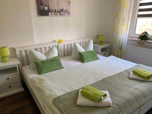 1 dormitorio con 1 cama blanca grande con almohadas verdes en Helenes Ferienwohnung auf dem Bauernhof - Lausitzer Seenland, en Laubusch