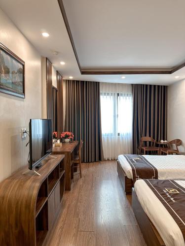 a hotel room with two beds and a flat screen tv at Linh Trang Hạ Long Hotel in Ha Long