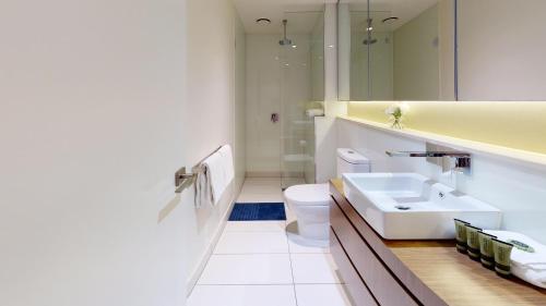 een badkamer met een wastafel, een toilet en een spiegel bij Luxe Living in Melbourne