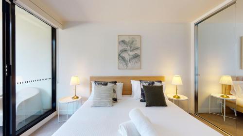 een slaapkamer met een groot wit bed met 2 lampen bij Luxe Living in Melbourne