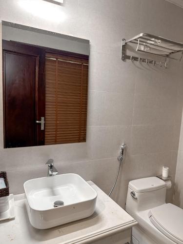 a white bathroom with a sink and a toilet at Linh Trang Hạ Long Hotel in Ha Long