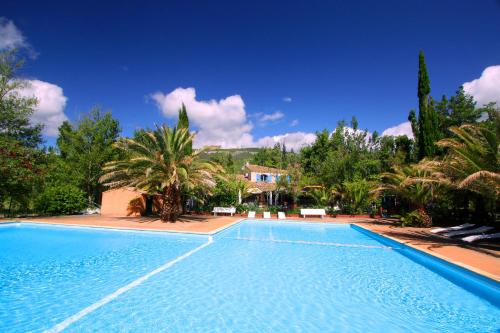 a blue swimming pool with palm trees and a house at Tente évasion in Tuchan