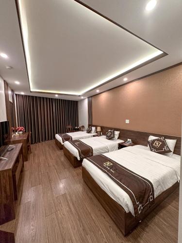 a hotel room with three beds in a room at Linh Trang Hạ Long Hotel in Ha Long