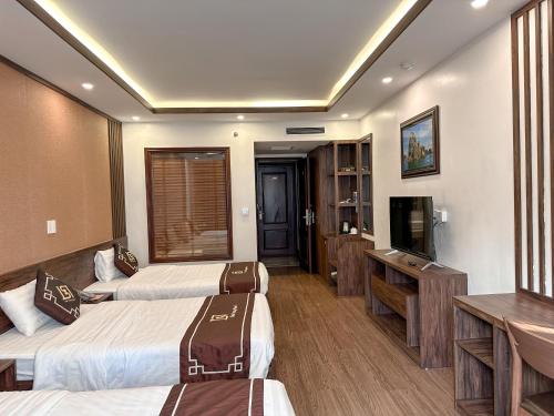 a hotel room with two beds and a flat screen tv at Linh Trang Hạ Long Hotel in Ha Long