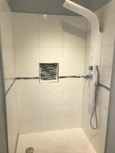 une salle de bain avec douche carrelée de blanc dans l'établissement Les embruns, à Saint-Jean-de-Monts