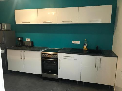 a kitchen with white cabinets and a black stove at Les embruns in Saint-Jean-de-Monts