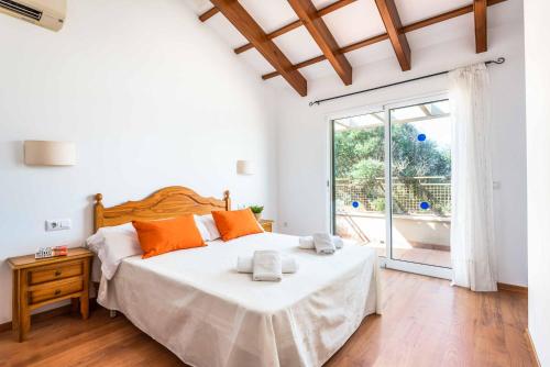 um quarto com uma cama com almofadas laranja e uma janela em Villa Flomertor 2 em Cala en Blanes