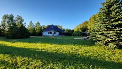 una casa in mezzo a un prato con un albero di REZYDENCJA BAŁTYCKA Sea and Forest KOPALINO a Kopalino