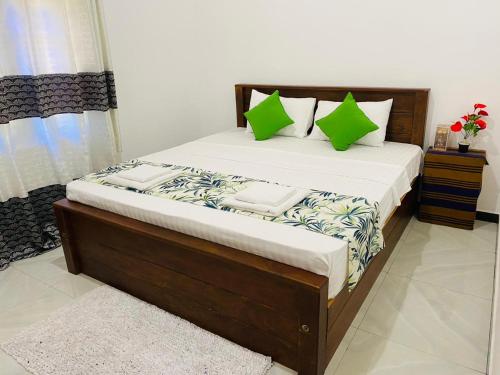 a bedroom with a large bed with green pillows at Udara Guest - Yala Safari in Yala
