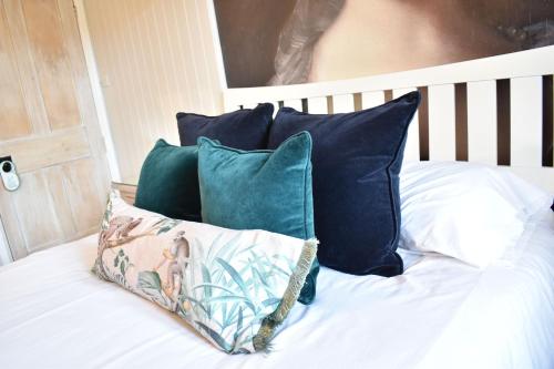 a bed with blue and white pillows on it at Davenford Cotswold Gardens in Stow on the Wold