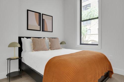een slaapkamer met een bed met een oranje deken erop bij UWS 1BR w Elevator WD nr Central Park NYC-857 in New York