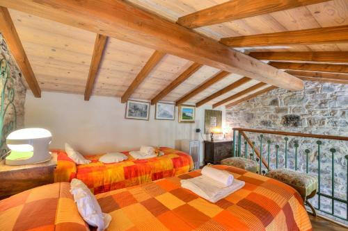 two beds in a room with wooden ceilings at Apartments In The Heart of Medieval Village - Happy Rentals in Apricale