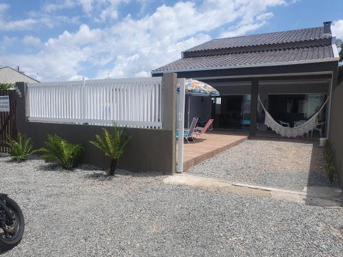 une maison avec une terrasse couverte dotée d'un hamac. dans l'établissement Mar Doce Lar, à Guaratuba