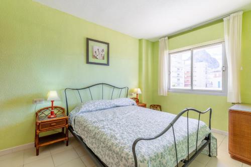 Schlafzimmer mit einem Bett mit grünen Wänden und einem Fenster in der Unterkunft Turmalina 45b in Calpe