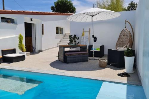 a house with a swimming pool and an umbrella at Villa piscine balnéothérapie et jacuzzi entièrement privée in Barras