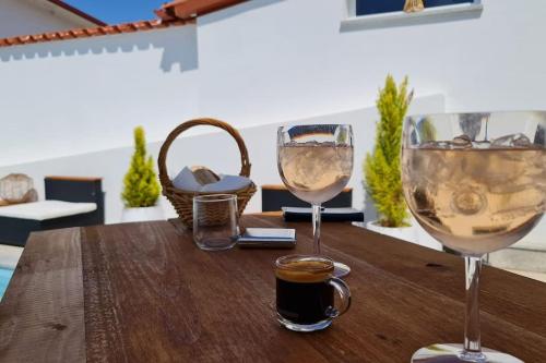 dois copos de vinho sentados numa mesa de madeira em Villa piscine balnéothérapie entièrement privée em Barras