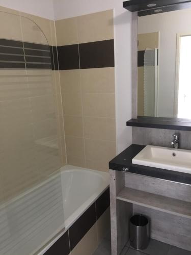 a bathroom with a bath tub and a sink at Appartement cozy pour curistes et touristes in Salies-de-Béarn