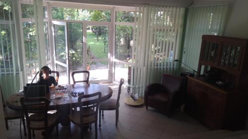a woman sitting at a table in a room with windows at SUBASA GREEN GARDEN in Szeged