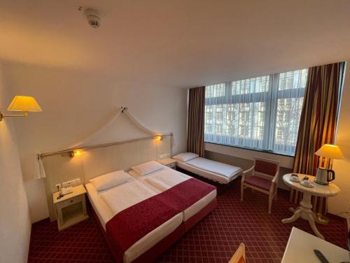 ベルリンにあるHotel Chateau Kurfürstendammのベッドと大きな窓が備わるホテルルームです。