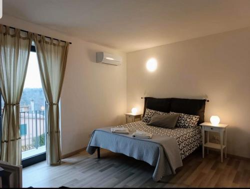 a bedroom with a bed and a large window at Velia's Home Casa Vacanze B&b in Castel SantʼElia
