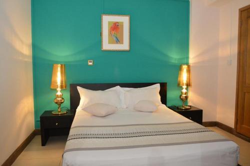 ein Schlafzimmer mit einem Bett mit blauen Wänden und 2 Lampen in der Unterkunft Burnas Beach in Pereybere