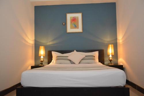 ein Schlafzimmer mit einem großen weißen Bett mit zwei Lampen in der Unterkunft Burnas Beach in Pereybere